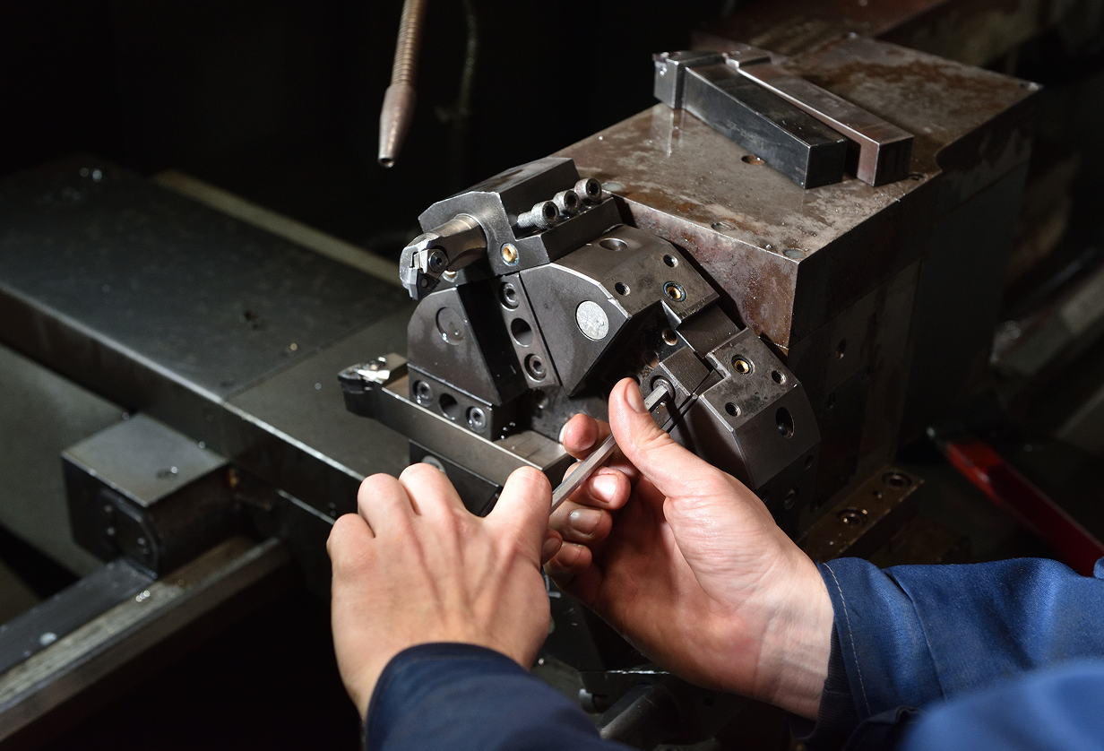 Hands using an Allen wrench to adjust industrial machinery.